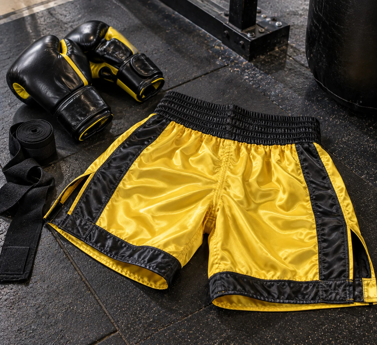 Yellow and black boxing shorts with boxing gloves in flat lay