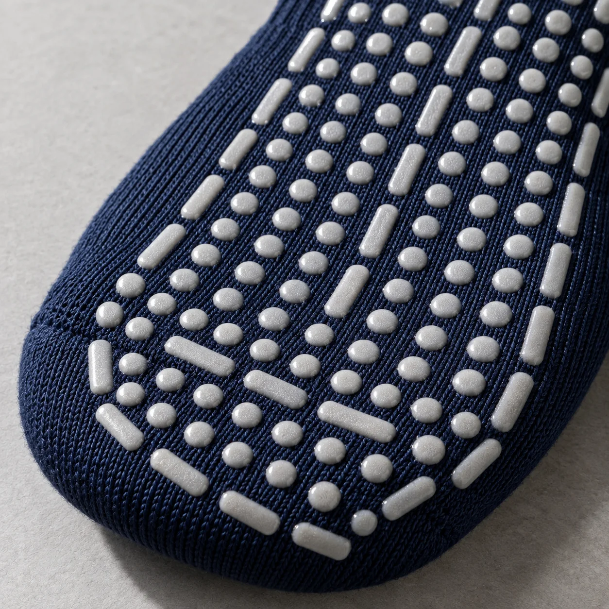 Close-up of silicone traction dots on a navy grappling grip sock sole