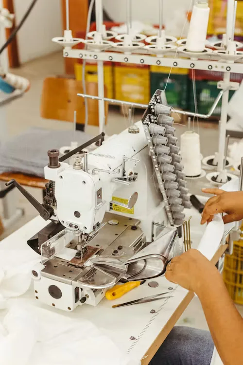 Operator feeding fabric through a multi-needle industrial stitching machine